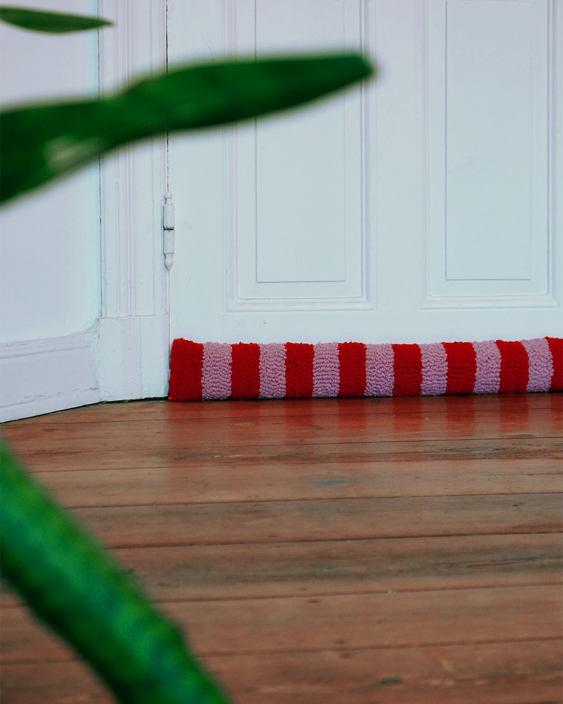 gestreifter Zugluftstopper Windfried vor Tür 